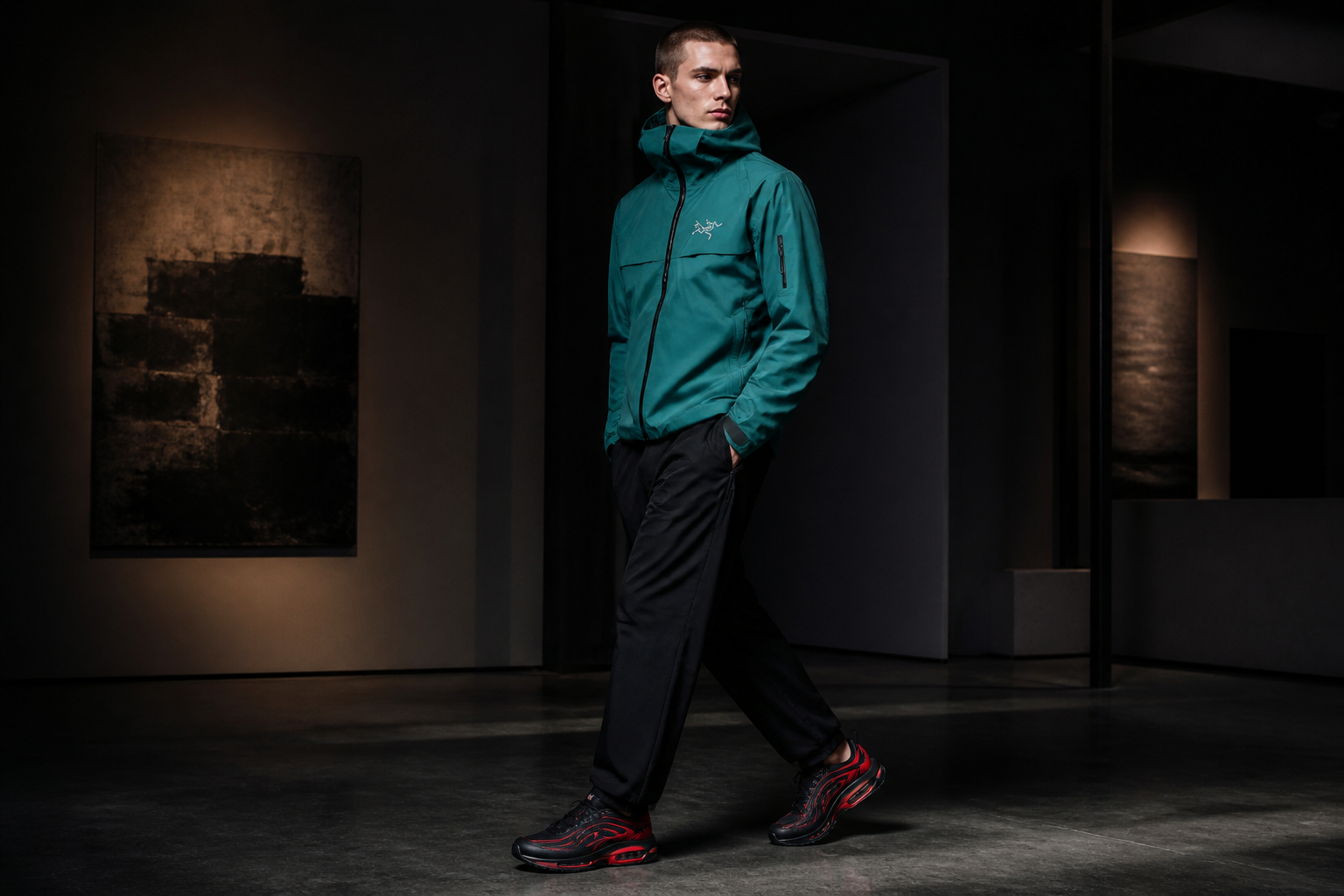 Model wearing a black and red Nike sneaker with a premium teal technical jacket